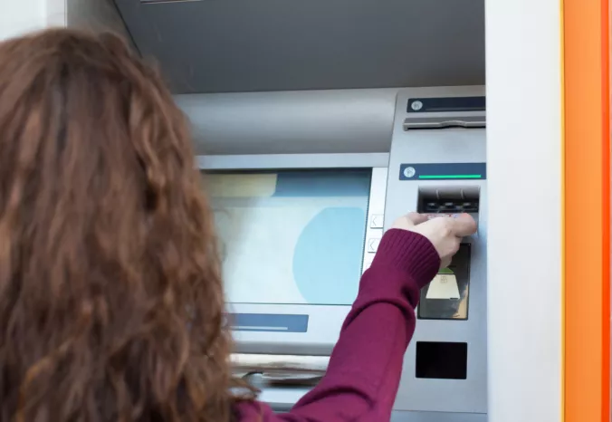 Ingyenes készpénzfelvételt csinál egy nő az ATM-nél